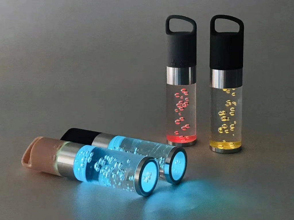 Compact colourful Bluetooth speaker with glowing crystal lights, shown in pink, black, silver grey, and green colour options.