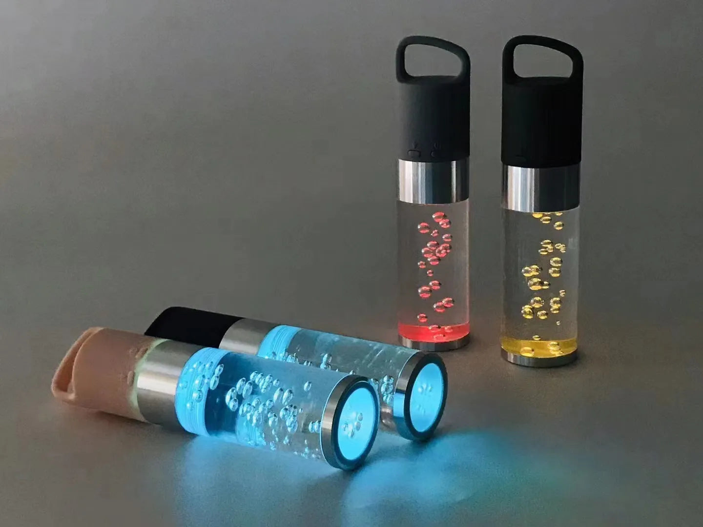 Compact colourful Bluetooth speaker with glowing crystal lights, shown in pink, black, silver grey, and green colour options.