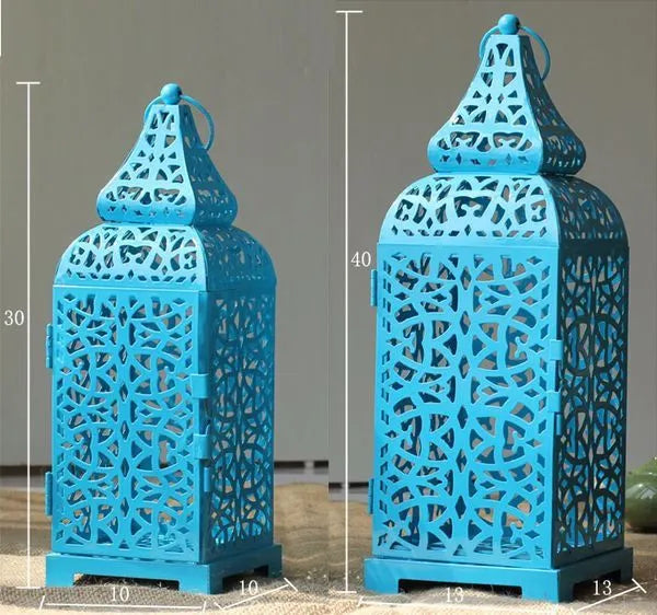 A tall, hollow geometric iron candlestick in blue, standing 38cm high on a wooden table.