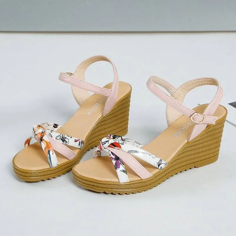 Women's pink wedge heel sandals with a buckle closure and textured non-slip sole on a white background.