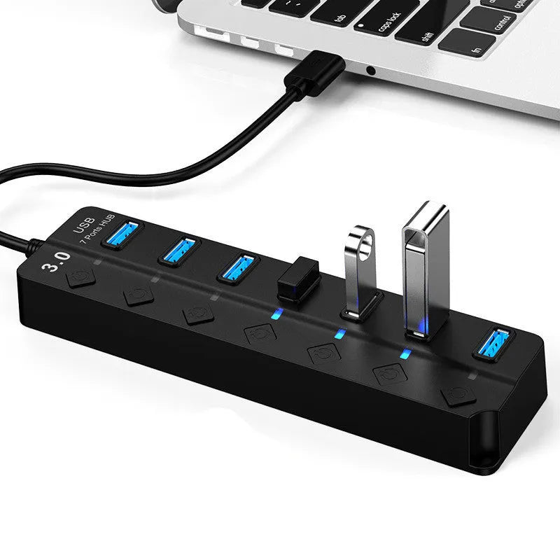 Black 7-port USB 3.0 hub with external power adapter on a wooden desk