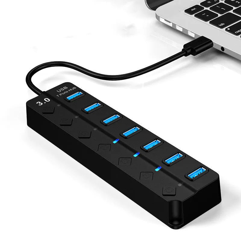 Black 7-port USB 3.0 hub with external power adapter on a wooden desk