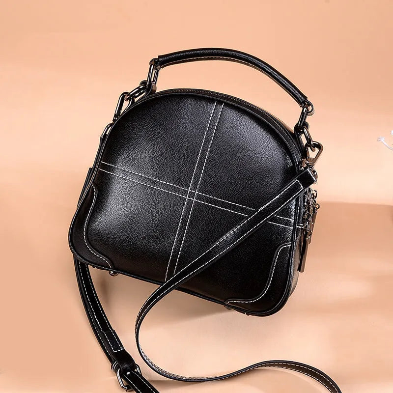 Wine red leather crossbody bag with a structured round shape, shown with its zipper open.