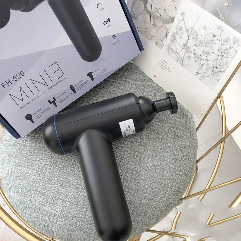 A black handheld fascia gun muscle massager with a USB charging port on a grey background.