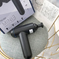 A black handheld fascia gun muscle massager with a USB charging port on a grey background.