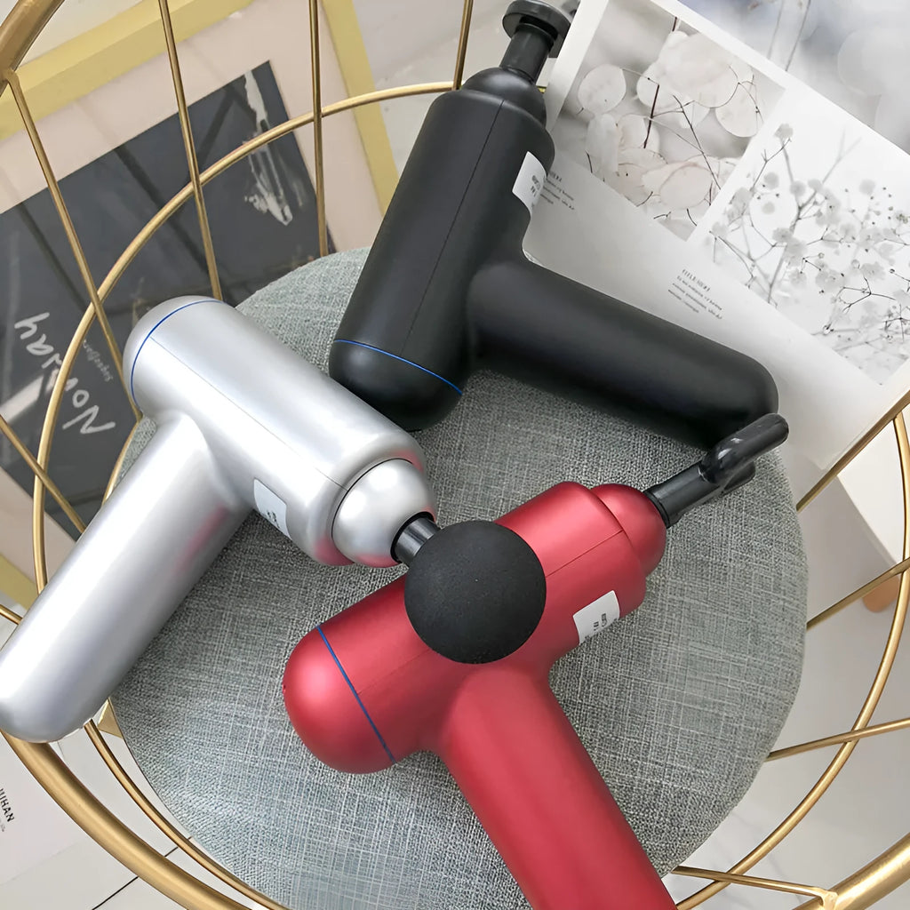 A black handheld fascia gun muscle massager with a USB charging port on a grey background.