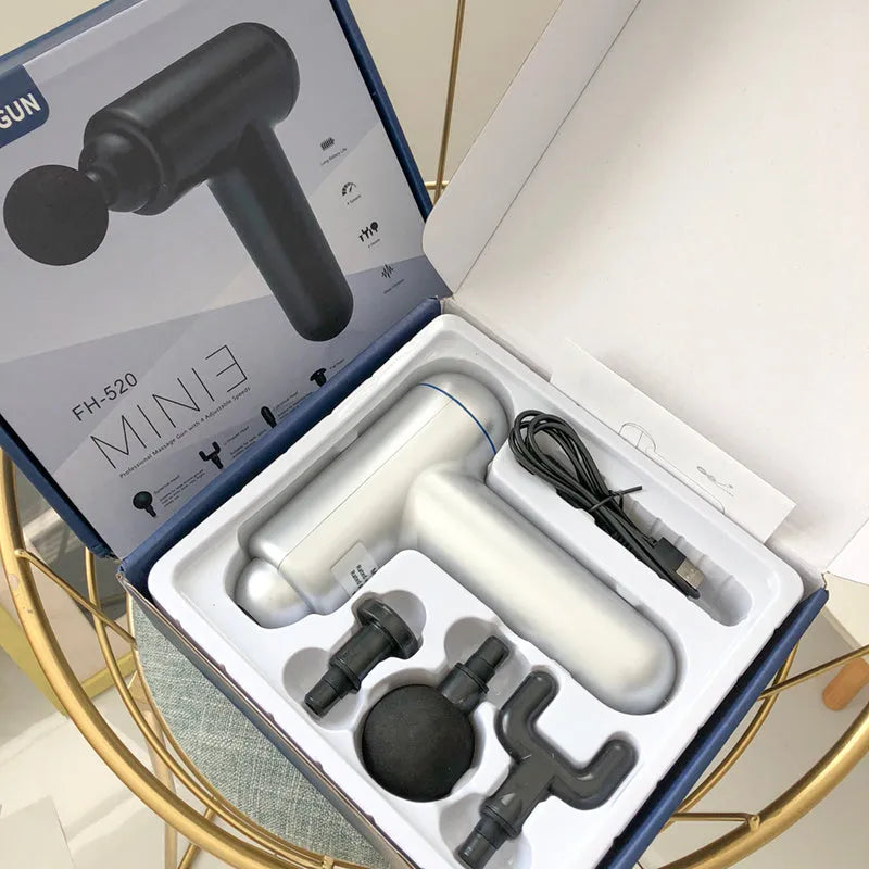 A black handheld fascia gun muscle massager with a USB charging port on a grey background.