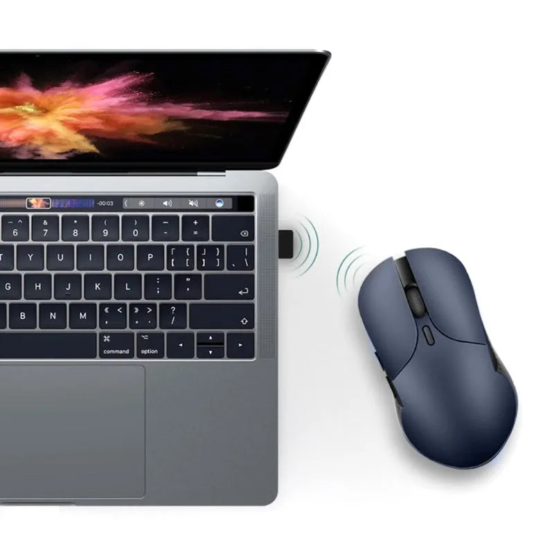 Blue wireless Smart Voice Mouse with voice control button on a desk next to a laptop.