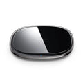 Black square wireless charging pad with glass top and zinc alloy rim on a wooden desk