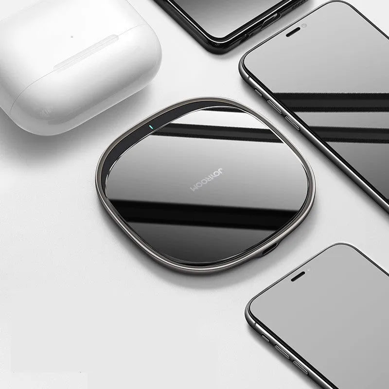 Black square wireless charging pad with glass top and zinc alloy rim on a wooden desk