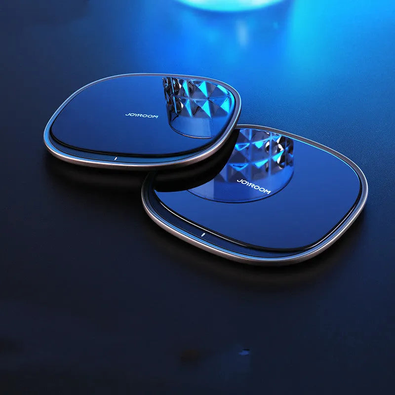 Black square wireless charging pad with glass top and zinc alloy rim on a wooden desk