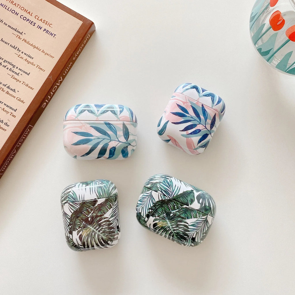 Blue TPU AirPods case with painted tropical banana leaf design, shown next to a green variant.