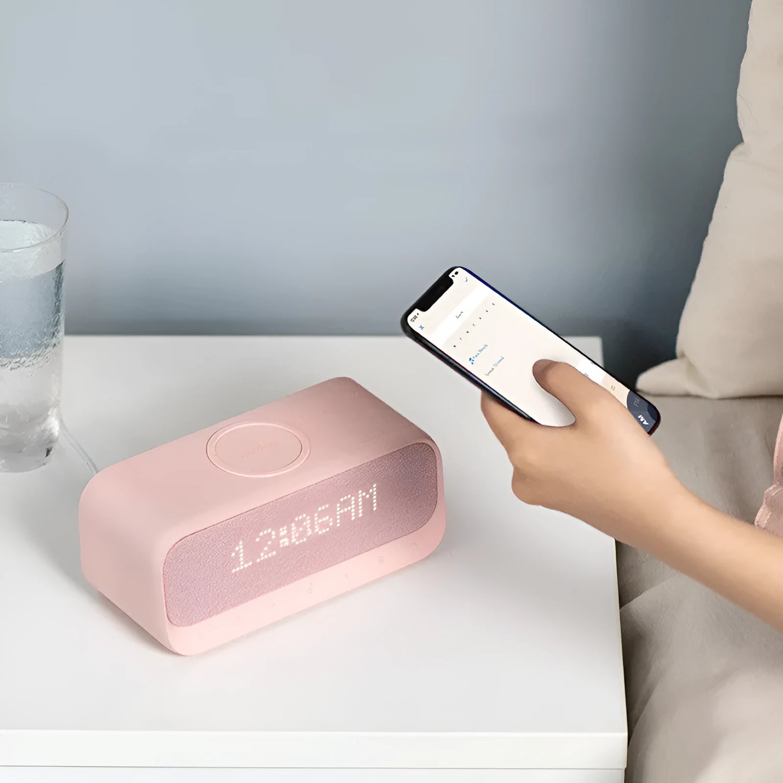 White Anker Soundcore Bluetooth speaker with wireless charging top and digital clock display.