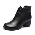 Brown women's leather Martin boots with a round toe and thick medium heel on a wooden surface.