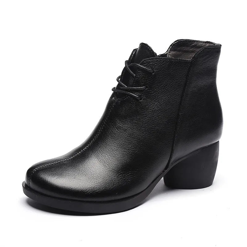 Brown women's leather Martin boots with a round toe and thick medium heel on a wooden surface.