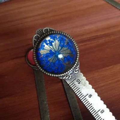 Handmade dried gypsophila and clover flower bookmark ruler on a book, showing 12cm length.