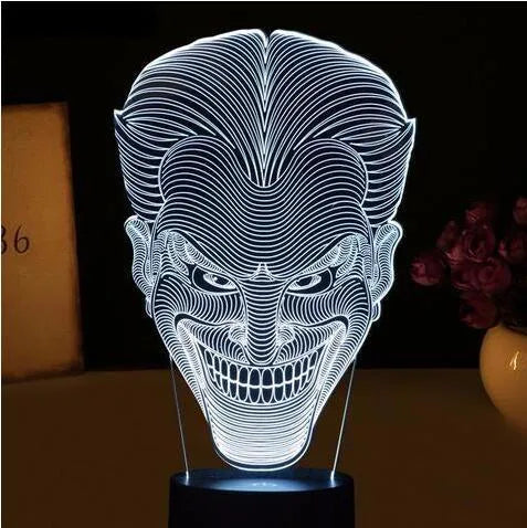 A 3D acrylic LED lamp on a base, showing a colourful gradient light effect, with a remote control beside it.