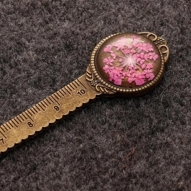 Handmade dried gypsophila and clover flower bookmark ruler on a book, showing 12cm length.