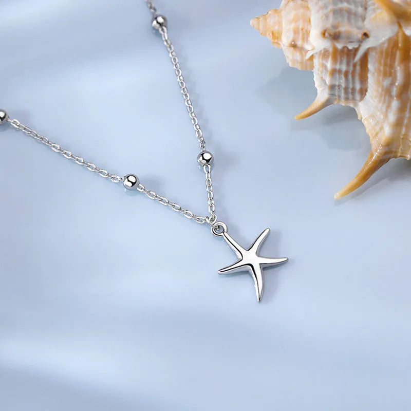 Adjustable sterling silver anklet with round beads and a small starfish charm on an ankle.
