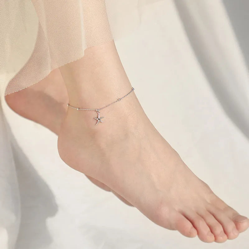 Adjustable sterling silver anklet with round beads and a small starfish charm on an ankle.