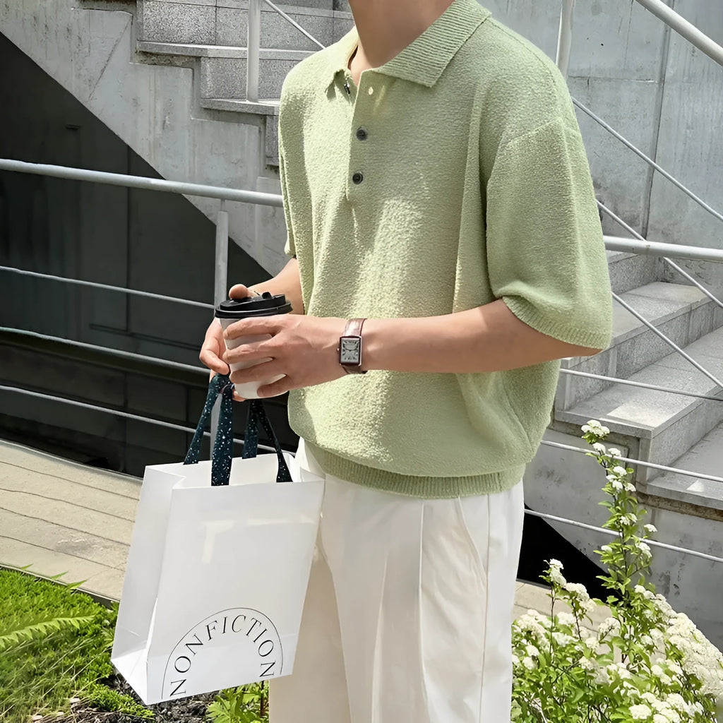 A caramel coloured men's loose-fit knitted polo shirt with short sleeves on a hanger.