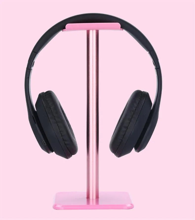 Detachable aluminum alloy headset hanger with TPU rubber cradle, shown in white, pink, and black, fixed to a table.