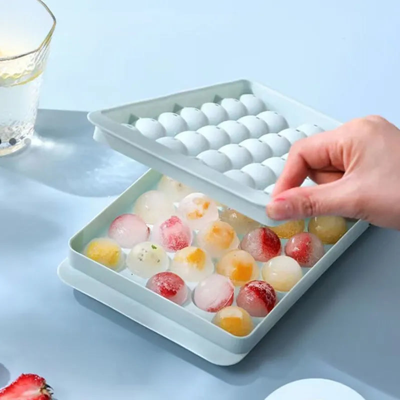 Blue lidded silicone ice cube tray making 33 round ice spheres on a kitchen counter.