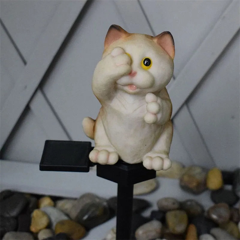 Brown resin cat-shaped solar garden light illuminating in a evening garden setting.