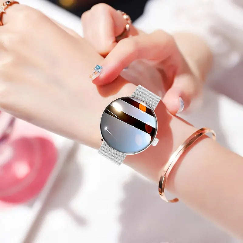 Circular smart watch with metal strap on a woman's wrist, showing colour touchscreen display.
