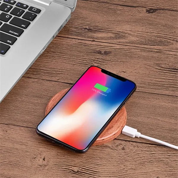 Natural bamboo wireless charger pad on desk with a smartphone placed on it