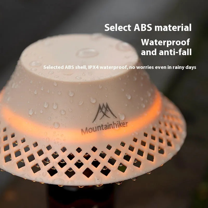 Beige plastic camping lantern shaped like a wine bottle with a glowing LED light inside on a wooden surface.
