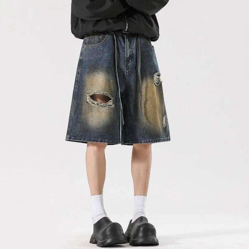A pair of retro blue loose fit men's jeans with ripped detailing on the legs.