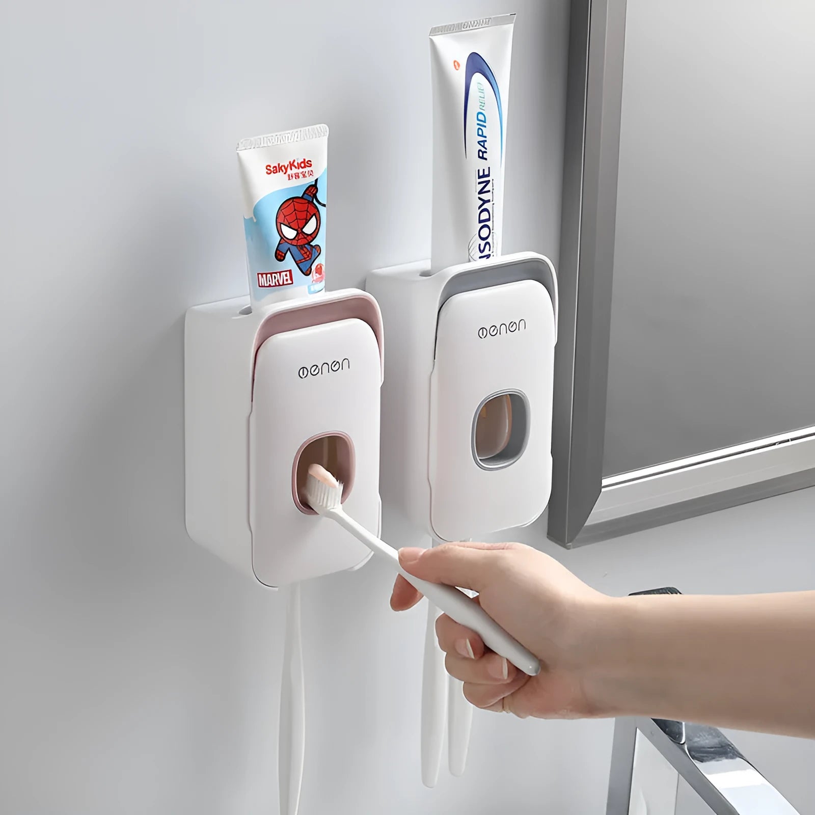 Automatic toothpaste dispenser in grey, blue, and pink colours on a bathroom countertop.