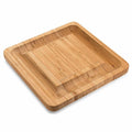 Square bamboo cutting board with drawer holding four-piece knife and fork set in wood colour