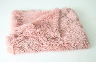 Soft grey long plush pet blanket for dogs on a wooden floor next to a kennel.
