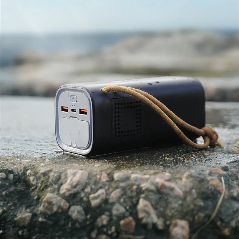 Black portable power bank with 220V AC outlet, USB ports, and solar charging panel.