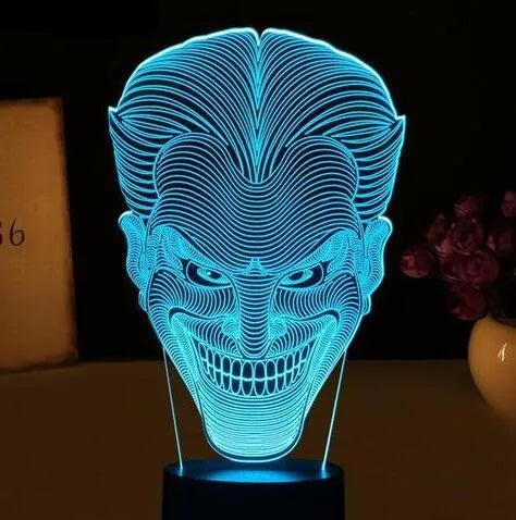 A 3D acrylic LED lamp on a base, showing a colourful gradient light effect, with a remote control beside it.