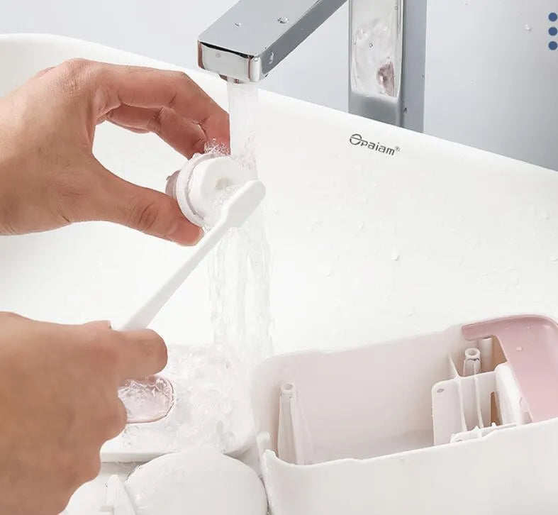 Automatic toothpaste dispenser in grey, blue, and pink colours on a bathroom countertop.