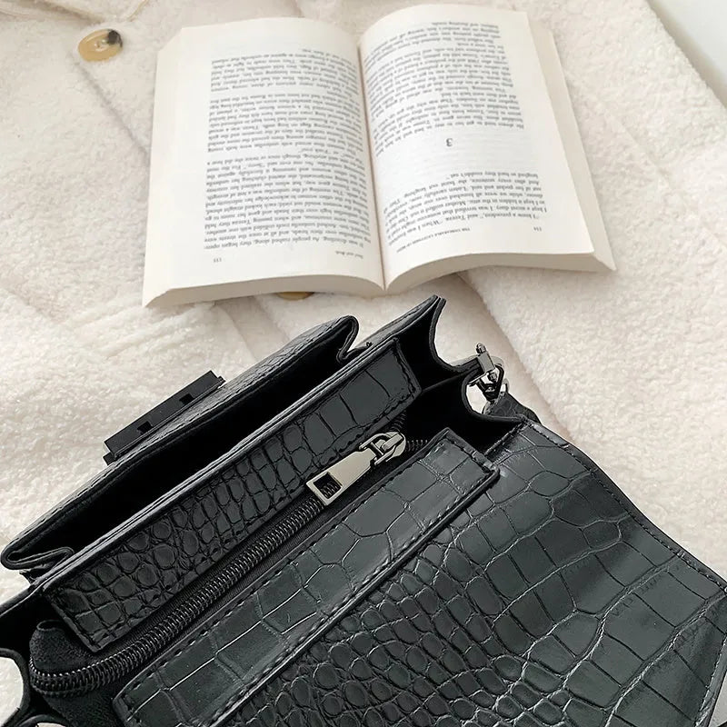 Vintage style black crossbody bag with an adjustable shoulder strap on a mannequin.