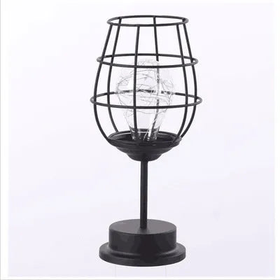Minimalist hollow iron table lamp with warm white light on a wooden desk