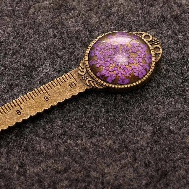 Handmade dried gypsophila and clover flower bookmark ruler on a book, showing 12cm length.