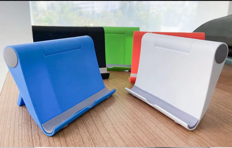 Black folding mobile phone stand holding a smartphone on a desk.