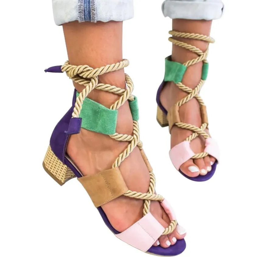 Women's beige suede sandals with thick heel and ankle strap on a foot.