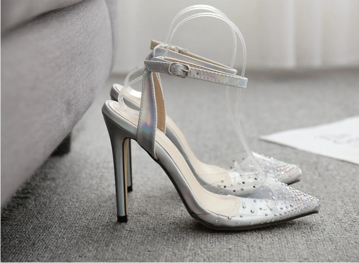 Women's pointed toe stiletto heel sandals with a glossy PVC upper and an ankle strap buckle.