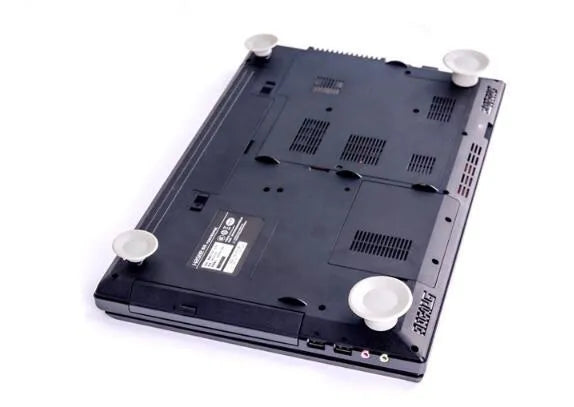 Grey laptop cooling stand with four silicone feet creating an air gap under a silver laptop.