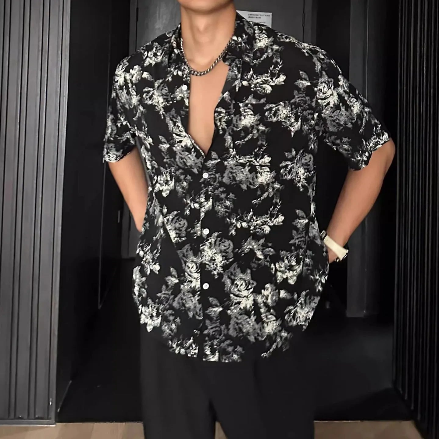 Loose-fitting black floral print short sleeve shirt on a hanger.