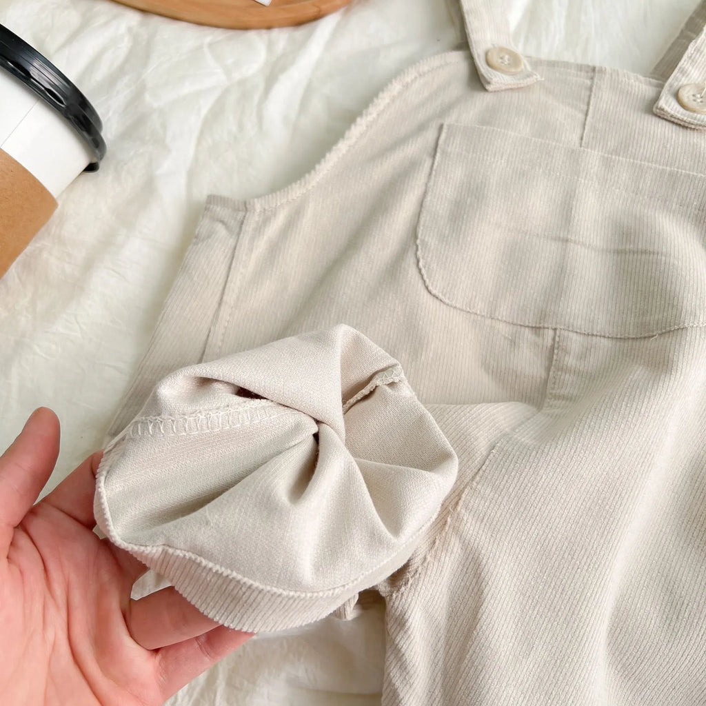 Unisex corduroy suspender overalls in creamy-white or brown plaid, with large pockets and double-breasted closure, for spring and autumn.