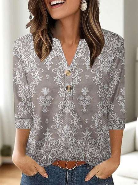 Woman wearing a loose-fit grey V-neck t-shirt with a colourful 3D geometric print, short sleeves.