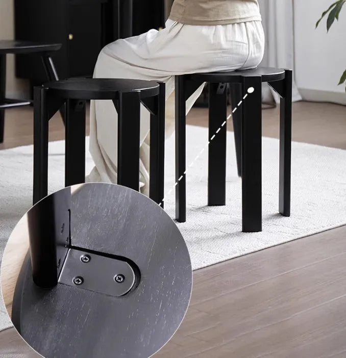 Stackable round iron dining stool in a modern style, shown in a choice of smoked black, walnut, cherrywood, or cream colour.