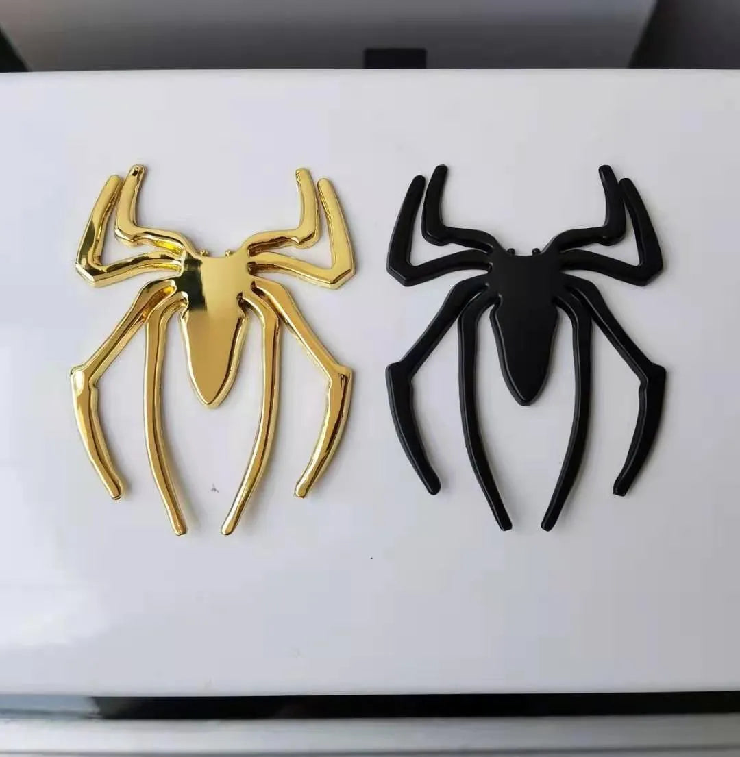 Three-dimensional metal spider bumper sticker in gold colour on vehicle surface